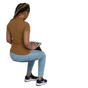 cut out black woman sitting and looking smth at her ipad