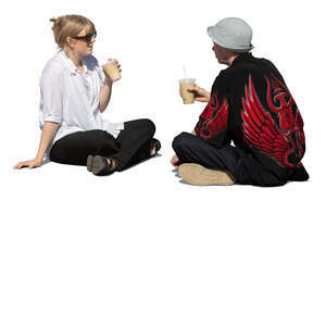 man and woman sitting outside on the ground and drinking coffee