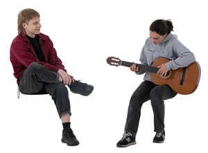 woman sitting and playing a guitar and friend listening