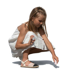 child in a white dress squatting and drawing on the street