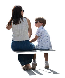 backlit mother and son siting on a bench seen from back angle