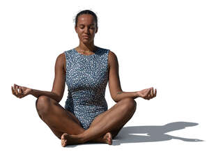 woman in a swimsuit sitting in a yoga pose outside in sunlight