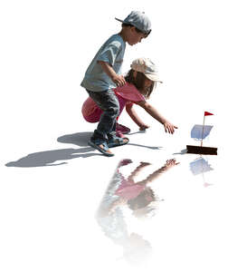 two cut out kids floating a toy boat