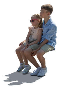 two cut out children sitting in backlight