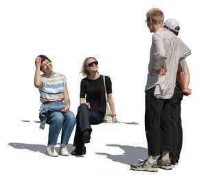 two guys talking to two girls who are sitting