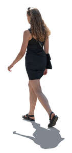 backlit woman in a little black dress walking