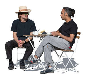 two men sitting in an outdoor cafe and talking
