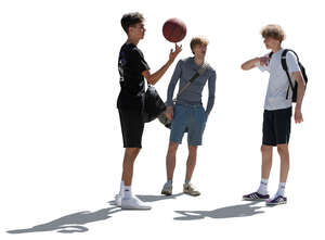 three backlit teenage boys with a basketball standing