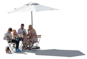 family with kids sitting in an outdoor restaurant under a parasol