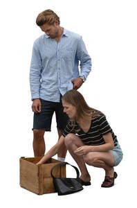 man and woman looking smth from the box on the market