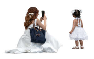cut out woman in a white dress taking a picture of her little daughter