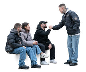 group of friends sitting and greeting a young man