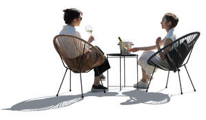 two backlit asian women sitting and drinking wine
