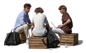 three teenage boys sitting outside and studying
