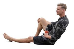 cut out man in shorts sitting and drinking cocktails
