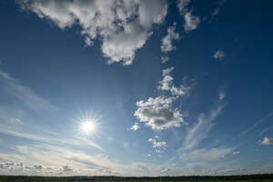 deep blue sky with some clouds and sun shining