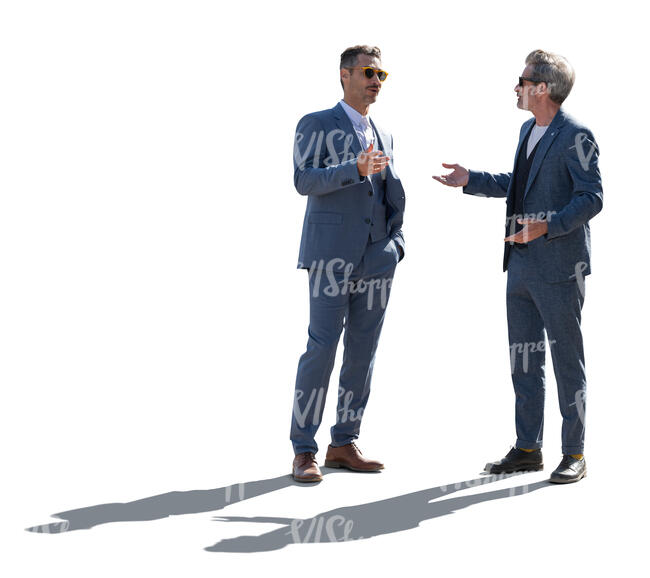 two backlit men in suits standing and talking