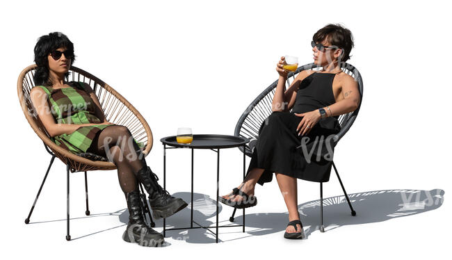 two women sitting in armchairs on a patio and talking