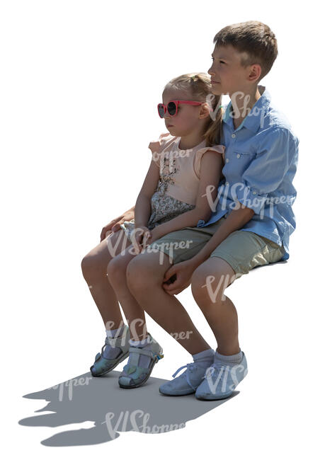 two cut out children sitting in backlight