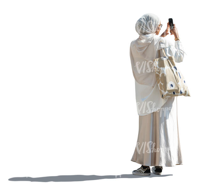 muslim woman in a white outfit taking pictures with her phone