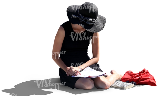 woman with a large hat sitting on the ground and reading
